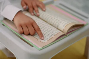 a person pointing at a book (Quran), emphasizing Islamic dietary laws about pork, 